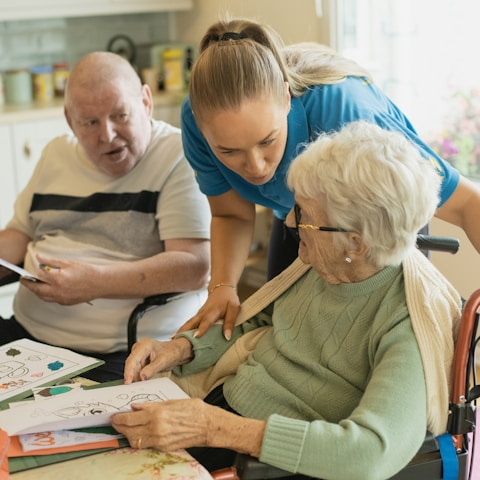 Caregiver assisting elderly couple with coloring